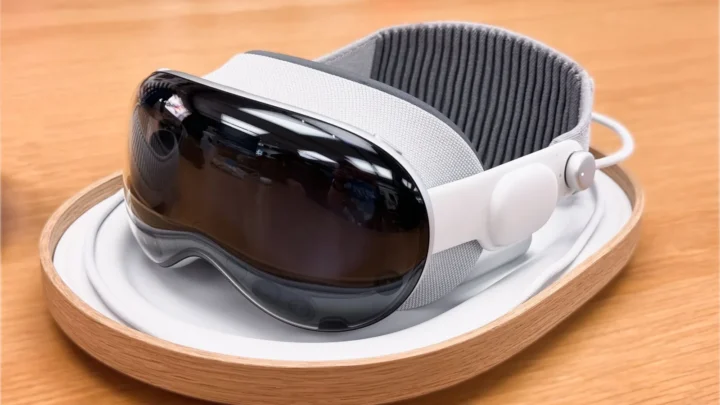 Apple Vision Pro-ის თეთრი შერეული რეალობის ჰედსეტი ხის ლანგარზე დევს.